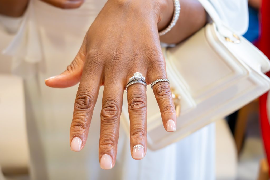 La main de la mariée tendue, bague de fiançailles et alliance au doigt, bracelet de diamants au poignet.